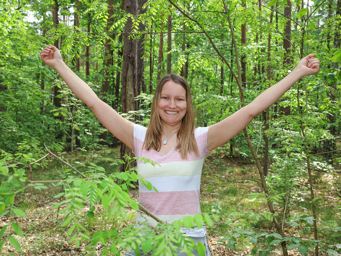 glücklicher Glückscoach beim powerposing im grünen Wald