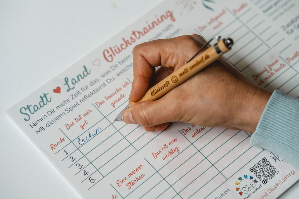 Foto einer Person beim Spielen des Spiels Stadt, Land, Glückstraining, welches von der Glückstrainerin Melli Seedorf entwickelt wurde