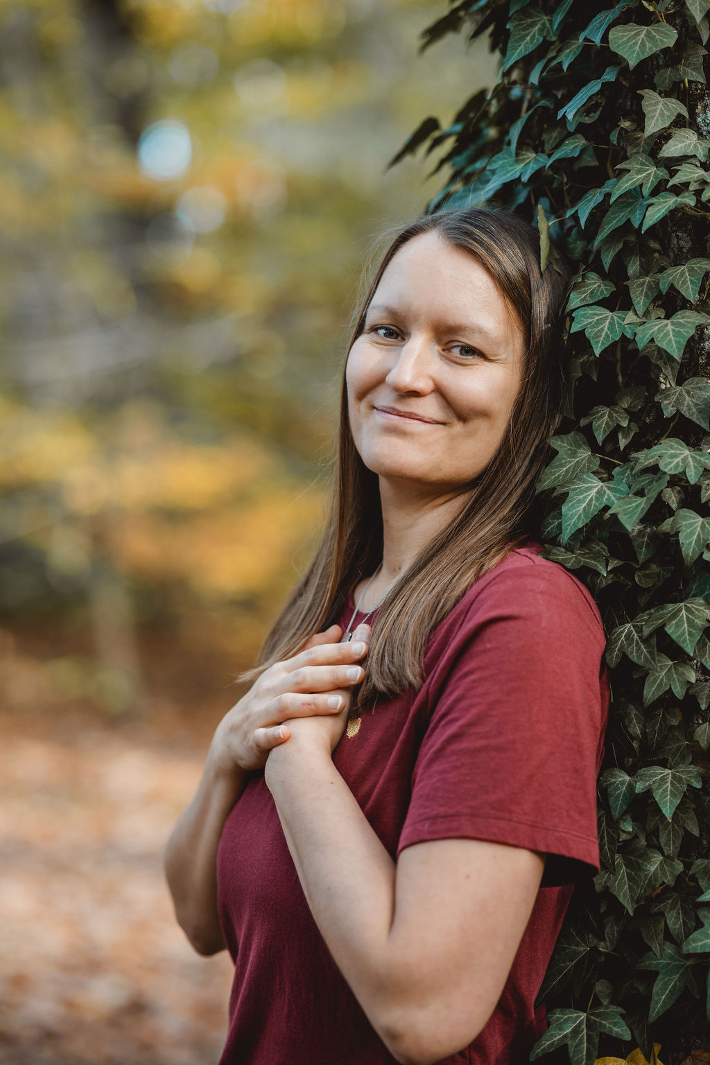 thetahealerin melli seedorf, an einem baum gelehnt, herzlich lächelnd