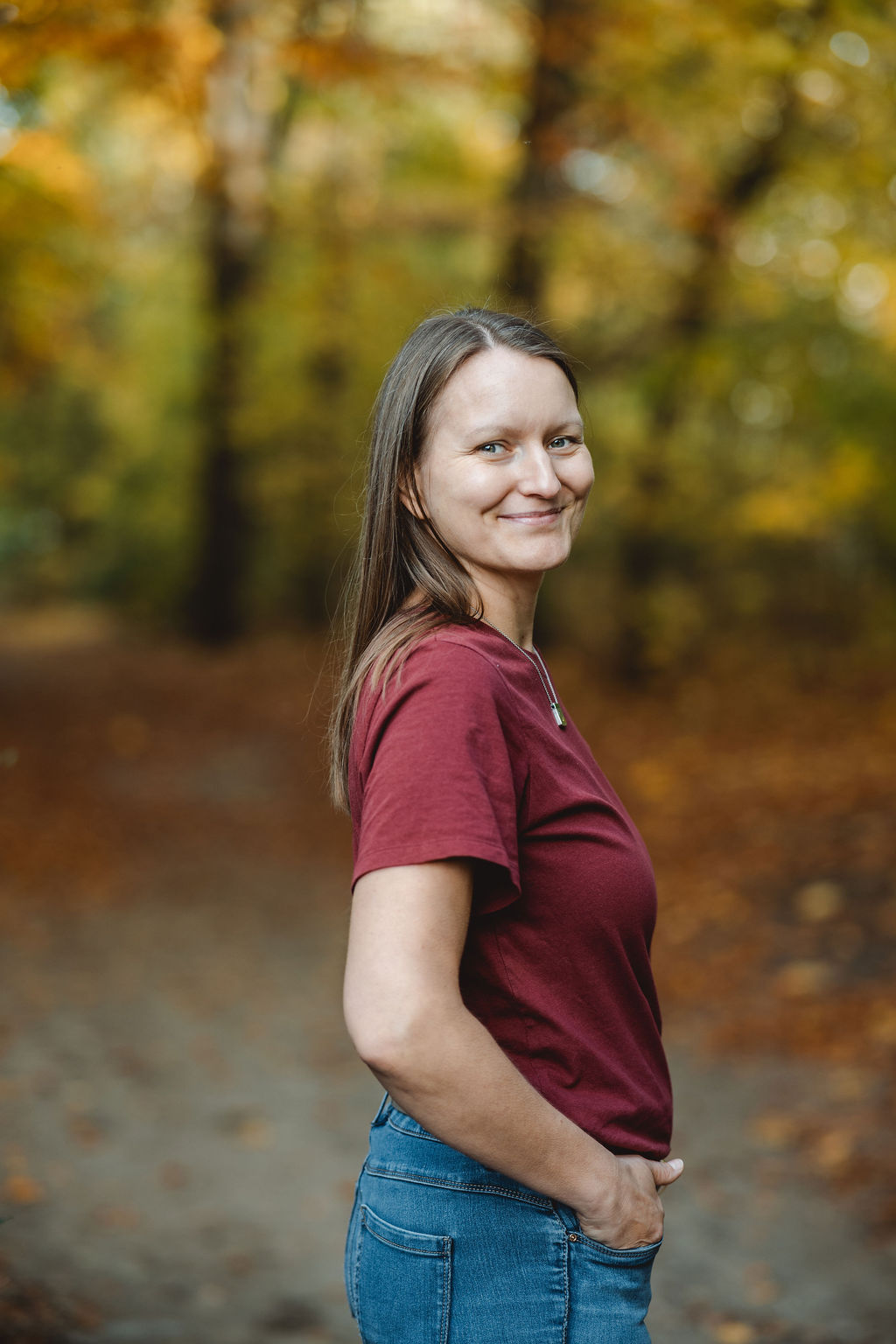 Melli Seedorf steht auf einem Waldweg und schaut dich einladend an, gemeinsam weiterzugehen
